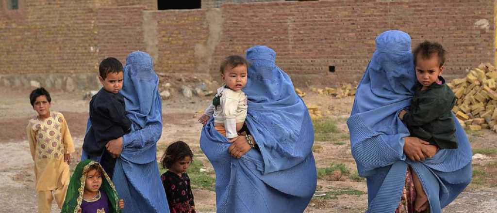 Mujeres cruzan a sus hijos por sobre el muro del aeropuerto de Kabul